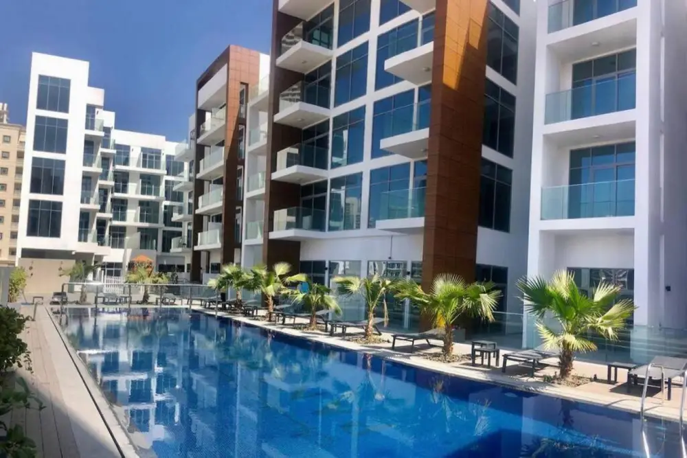 Piscine bordée de palmiers au pied de la résidence Elysée à JVC, où se trouve un logement géré par Medini Homes