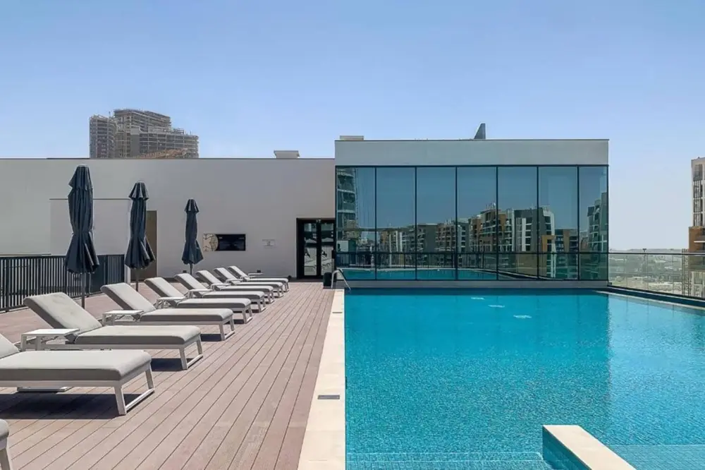 Piscine et transats de la résidence Sobha Waves à MBR City, où se trouve un logement géré par Medini Homes